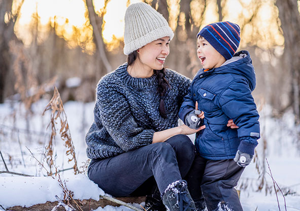 A mom and her little boy are outside in the snow