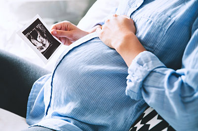 Pregnant belly and mom looking at ultrasound photo